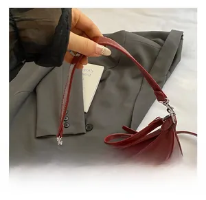 Close-up of dark red glossy faux leather hobo bag with silver zipper and slim handle
