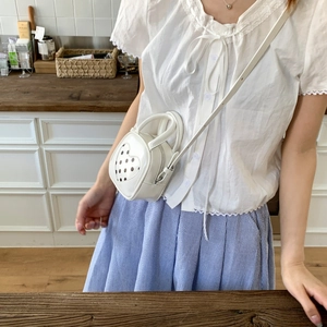 Close-up of white mini heart bag with polka dot pattern and adjustable strap detail