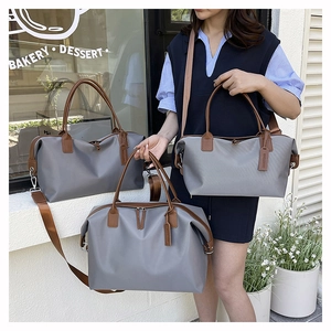 Three grey nylon travel tote bags in various sizes with leather handles and straps