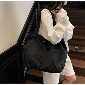 Detail of black drawstring tote bag with exterior pocket and spacious nylon compartment