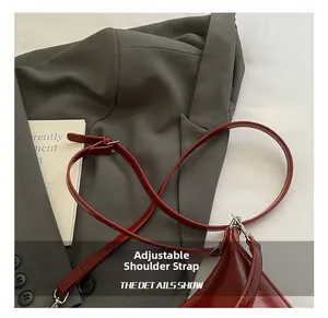 Detail of red patent leather tote with adjustable shoulder strap and silver buckle