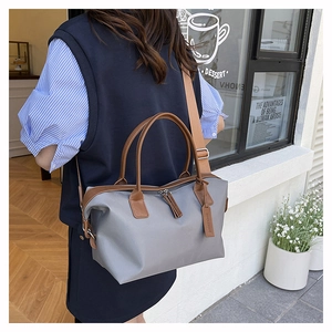 Gray canvas tote bag with brown leather handles worn by a model in a street scene