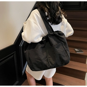 Close-up of black nylon tote bag featuring a drawstring closure and a wide shoulder strap
