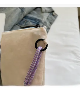 Detail of durable black metal hook and tricolor woven strap on beige canvas bucket bag