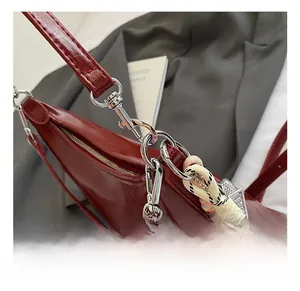 Detailed macro view of silver metal hooks and braided charms on a red glossy bag