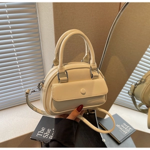 Detail of cream white bowling bag featuring front flap pocket and dual top handles