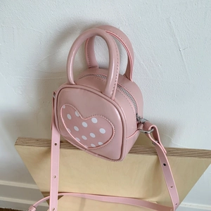 Close-up of pink heart-shaped mini bucket bag with white polka dots and silver zipper