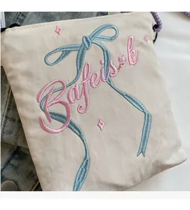 Close-up of cream canvas bucket bag featuring detailed blue and pink bow embroidery