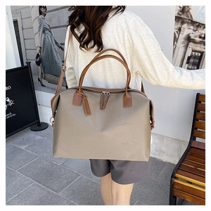 Outdoor shot of a khaki oversized tote bag with brown leather handles and side detail