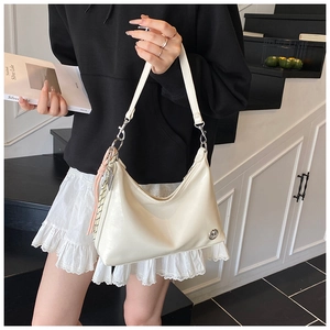 Detail of off-white hobo bag with tassel ornament and textured faux leather finish