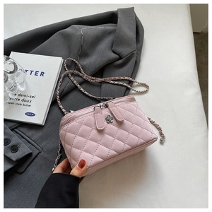 Close-up of pink quilted crossbody bag with silver flower clasp and woven chain strap