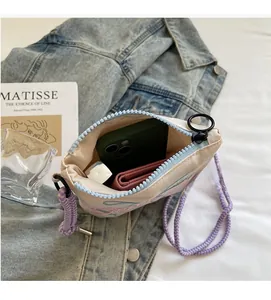 Detail view of pink nylon crossbody bag interior with blue zipper and purple rope strap