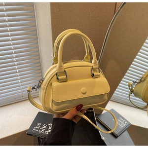 Detailed view of yellow faux leather Boston bag with silver hardware and top handles