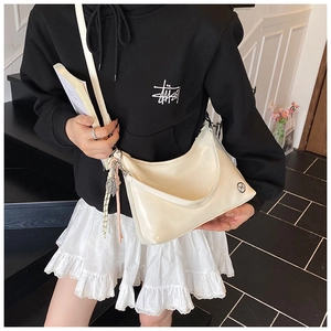 Close-up of white glossy faux leather shoulder bag with sleek metal buckles and strap