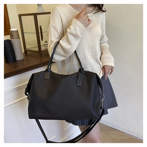 Close-up of black nylon tote bag with leather tag and adjustable strap in a cafe