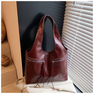 Détail d'un sac cabas vintage bordeaux avec fermetures à glissière et élégantes franges