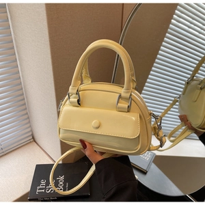 Detail of light yellow mini Boston bag with glossy PU texture and front flap pocket