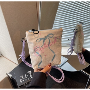 Detail of cream canvas mini bucket bag with purple braided strap and letter embroidery