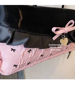 Détail du sac en tissu rose avec imprimés nœuds noirs et pendentif cœur