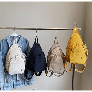 Detail view of four colorful teardrop nylon sling bags hanging on a metal rack