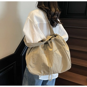 Back view of a model carrying a beige nylon drawstring tote bag on a staircase