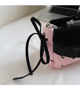 Gros plan du sac à main rose avec un nœud en cuir noir et des détails plissés