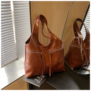 Détail d'un sac cabas marron vintage avec fermetures éclair et longs glands sur miroir