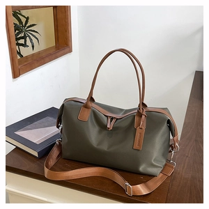 Detail of dark olive nylon duffle bag with brown leather handles and brand hangtag