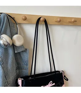 Détail du sac cabas noir et rose avec décoration de nœud et bandoulière lisse et chic