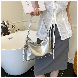 Detail of silver oil-wax leather shoulder bag with striped scarf charm and metal hardware