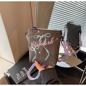 Detail view of mini nylon crossbody bag with bow embroidery and purple braided strap