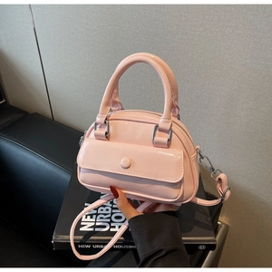 Detail of light pink glossy patent leather mini bowling bag with silver metal buckles