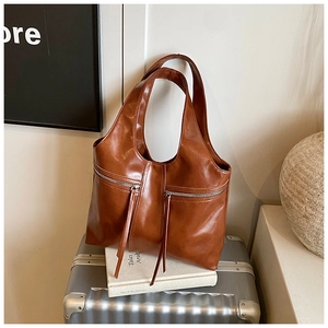 Détail d'un sac cabas en cuir marron avec doubles poches zippées et longues lanières