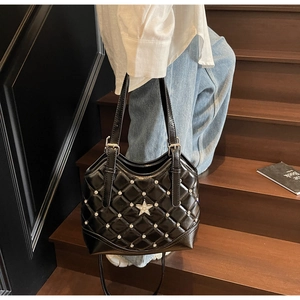 Detail einer schwarzen gesteppten Ledertasche mit Silbernieten und Sternemblem