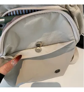 Detail of magnetic metal clasp on beige backpack with blue striped lining inside