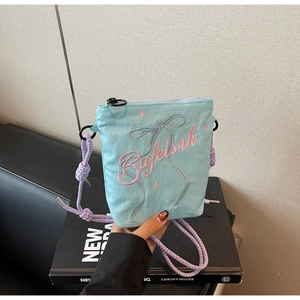 Detail of light blue canvas bucket bag featuring pink Bafeisrk embroidery and bow