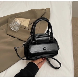 Detail view of the black retro pillow bag featuring a glossy texture and front snap pocket