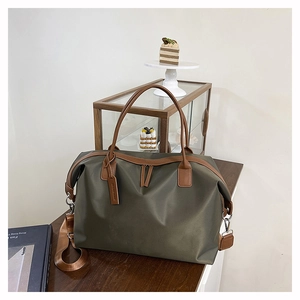 Detail of army green nylon tote bag with brown leather handles and side strap hooks