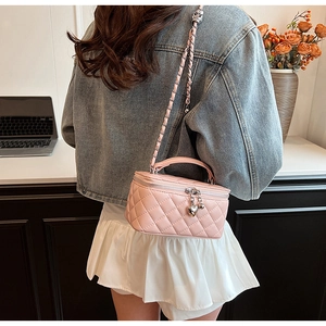 Pink quilted bag with heart charm and chain strap shown on model in modern office setting