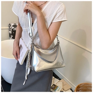 Detail of silver metallic hobo bag with tassel charm and adjustable shoulder strap