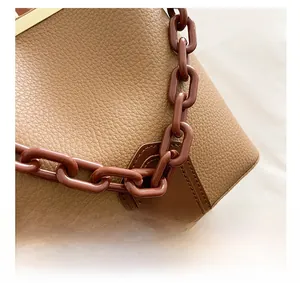 Détails d'un sac à main en cuir grainé beige avec poignée chaîne et surpiqûres précises