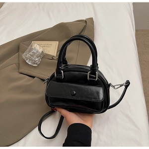 Detailed close-up of glossy black mini Boston bag with shiny patent finish and front pocket