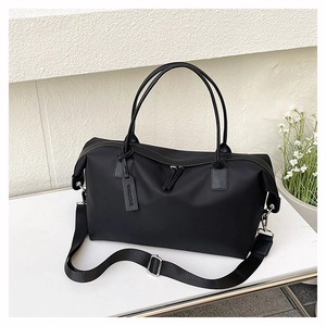 Detail view of black nylon tote bag showing metallic hardware and leather logo tag