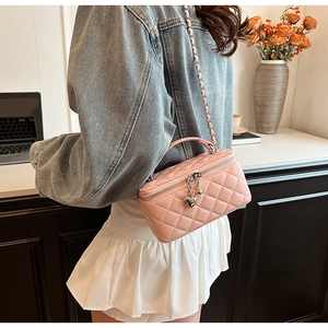 Close-up of pink quilted chain bag featuring a heart charm and mixed metal strap