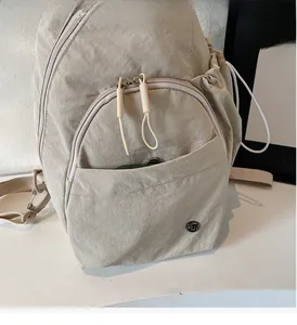 Detail of light beige nylon backpack featuring a wrinkled texture and dual zipper pulls