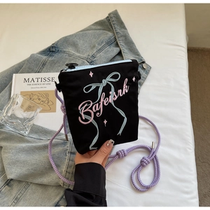 Close-up of black canvas bucket bag with cute embroidery and purple rope strap