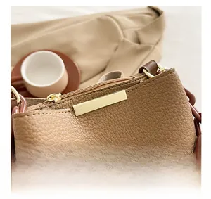 Détail du sac en cuir marron avec fermeture éclair dorée et chaîne en résine