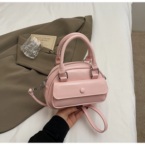 Detailed shot of a pale pink mini satchel bag with a top handle and adjustable strap
