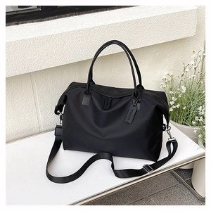Detail of black tote bag with adjustable shoulder strap and wholesome brand tag