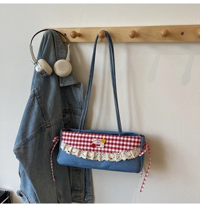 Détail du sac en jean avec bords en dentelle, écussons cerises et accents à carreaux